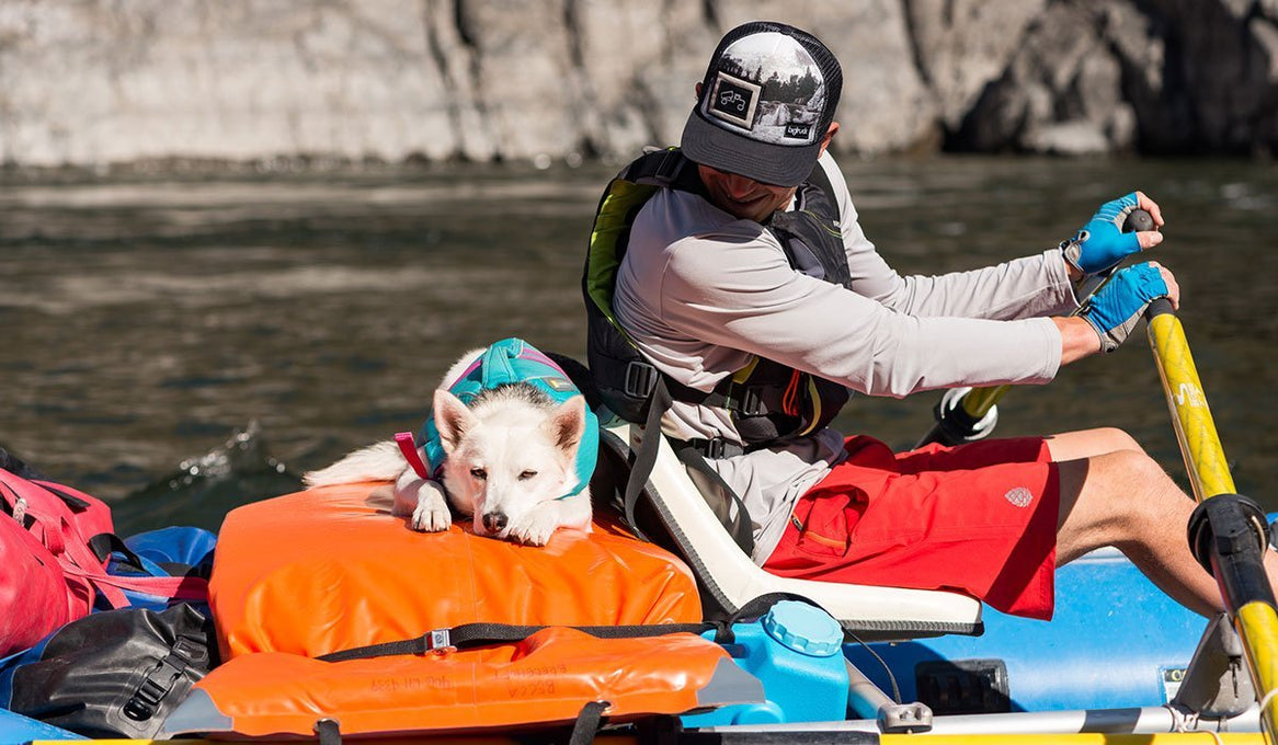 Cade rows raft while Tala sleeps in float coat at his side.
