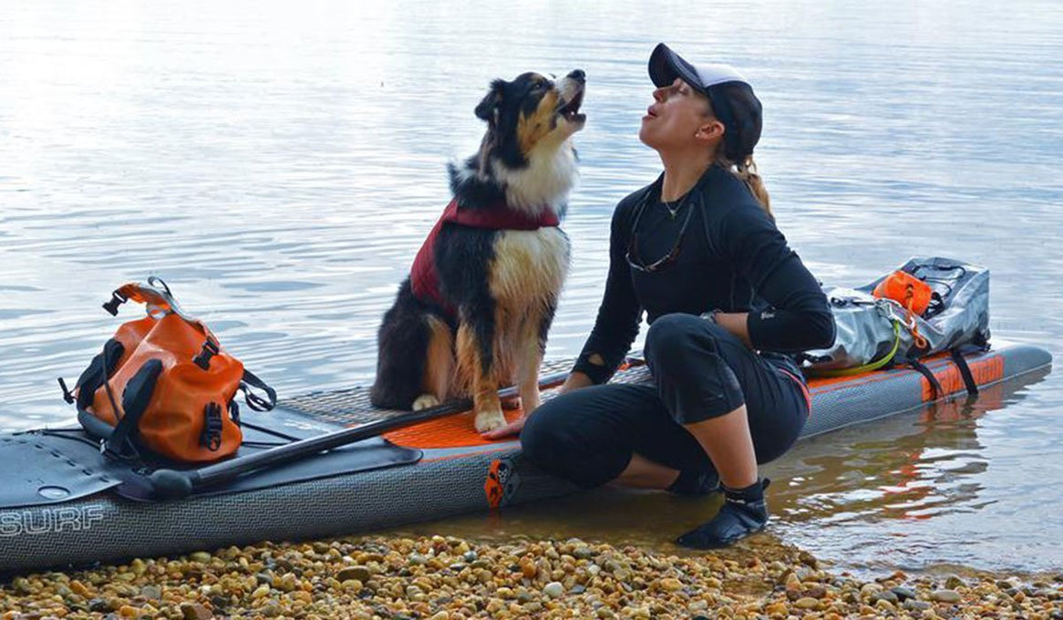 Maria and Kona sit on a paddleboard howling in to the air.