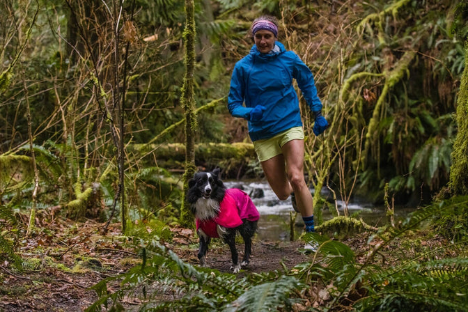 PD runs in sun shower jacket in front of Krissy on trail.